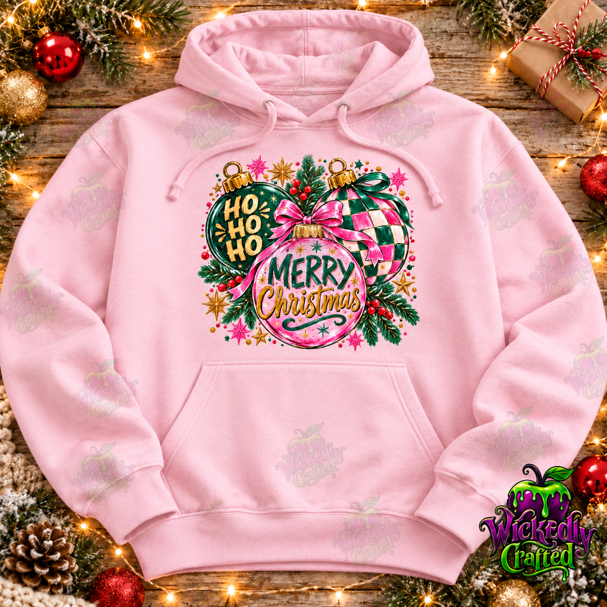 Pink and green Christmas ornament design on a light pink hoodie, Wickedly Crafted watermarked mockup